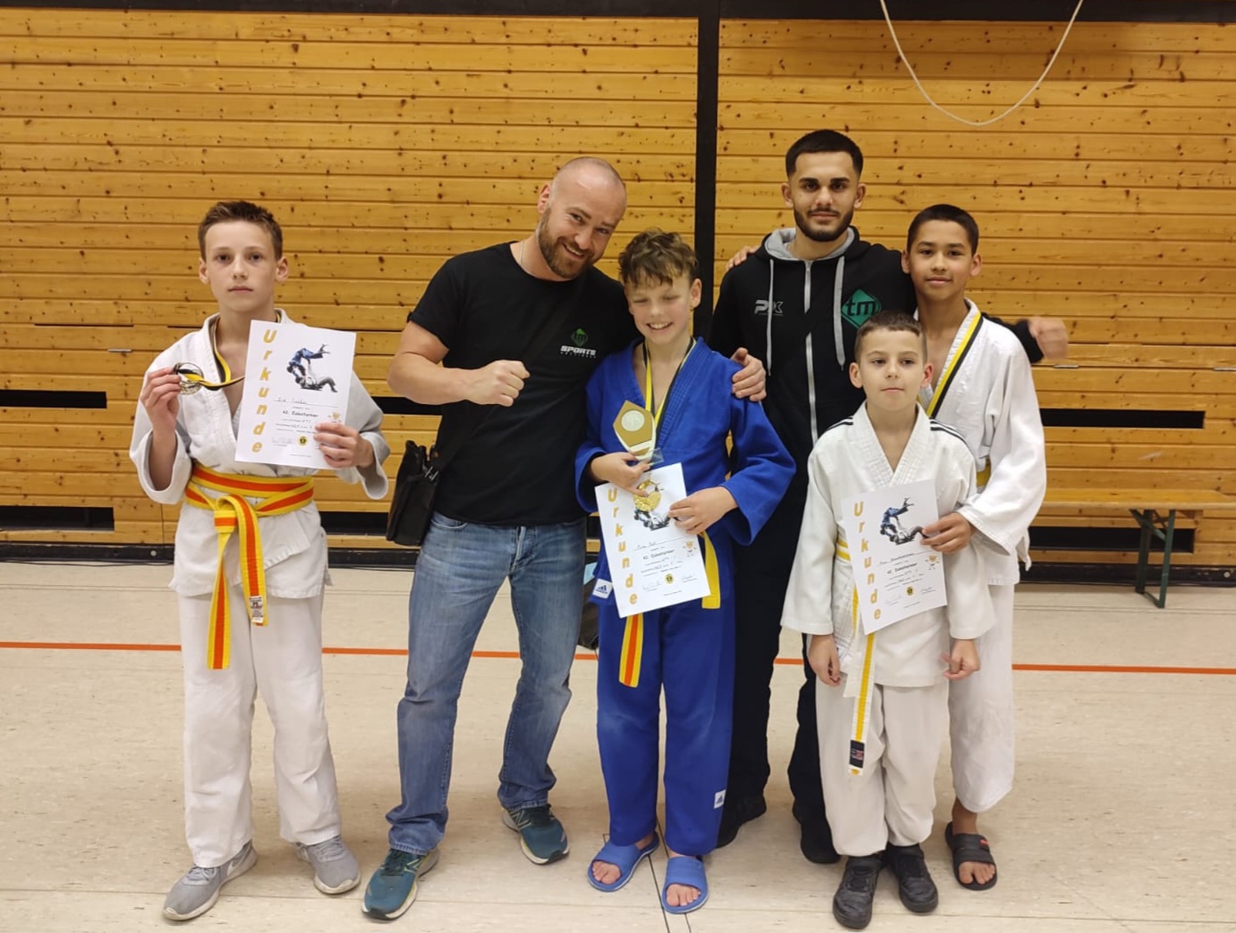 Judo-Kinder mit Trainern und Medaillen nach einem Wettkampf