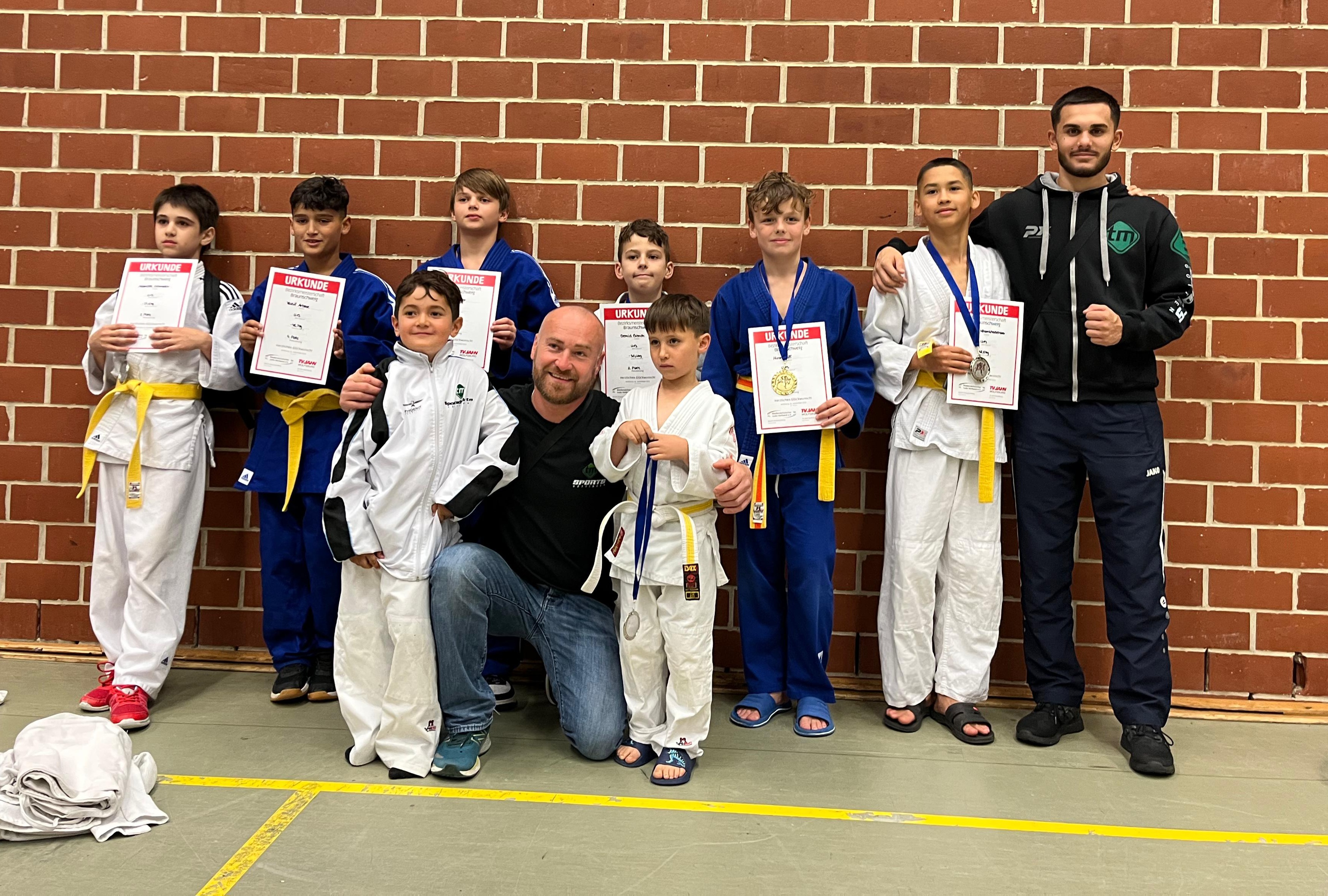 Kinder im Judoanzug mit Trainer und Urkunden nach einem Turnier