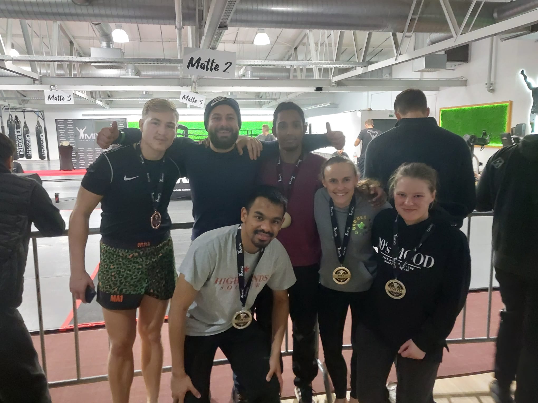 Kampfsportler und Trainer mit Medaillen auf der Matte